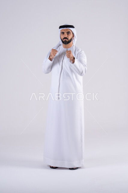 تعزيز صحة العظام والمفاصل، ممارسة رياضة الدفاع عن النفس، زيادة قدرة العضلات على التحمل، إتقان فنون الملاكمة، بورتريه لرجل عربي خليجي اماراتي يرتدي الكندوره والغتره يرفع قبضات يده بإيماءات القوة