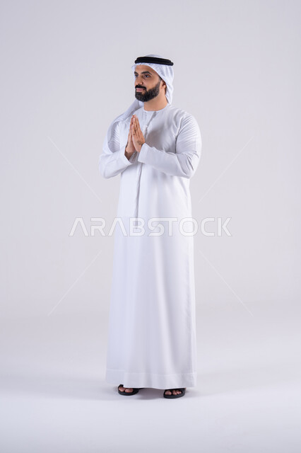 مفهوم الحمد والشكر وطلب العون , التعبد لله والرغبه في تحقيق الأمنيات, بورتريه لرجل عربي خليجي اماراتي يرتدي الكندوره والغتره، يرفع يده بإيماءات الدعاء والتضرع الى الله, تعابير طلب المغفره