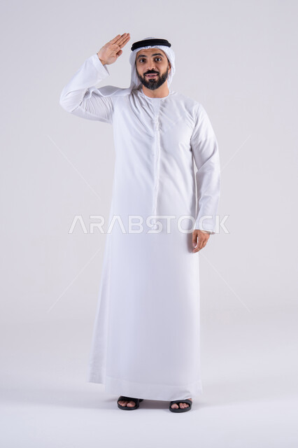 الأناقة والوسامة والرجولة، إلقاء التحية والسلام، مفهوم التقدير والاحترام،  بورتريه لرجل عربي خليجي اماراتي يرتدي الكندوره والغتره يرفع يده وينظر إلى الكاميرا بإيماءات السرور والترحيب