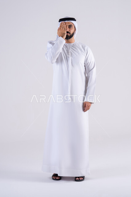 الاحتياج للكشف الطبي، ايماءات قياس النظر ، بورتريه لرجل عربي خليجي اماراتي يرتدي الكندوره  والغتره يضع يده على نصف وجهه بتعابير فحص العين