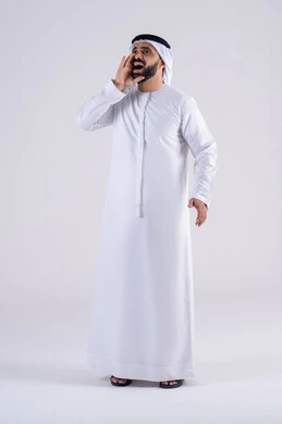 النداء والكلام والتحدث بصوت مرتفع،بورتريه لرجل عربي خليجي اماراتي يرتدي الكندوره والغتره يضع يده على فمه بإيماءات المناداة لشخص ما، دردشة ومحادثات وتواصل اجتماعي