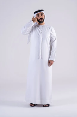 التواصل مع الأصدقاء ، إنتظار مكالمه وإستخدام المايكروفون، بورتريه لرجل عربي إماراتي خليجي يرتدي الكندوره والغتره , يقوم بإيماءات وجه ويدين تدل على إجراء مكالمه هاتفيه, تلقي إتصال , إشارة تعني إتصل بي