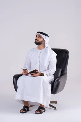 Acquiring knowledge and science, the concept of literacy, spending free time educating and learning, a portrait of an Arab Gulf Emirati man wearing a kandura and ghutra, practicing the hobby of reading useful books in his free time, gestures of contemplation and concentration.