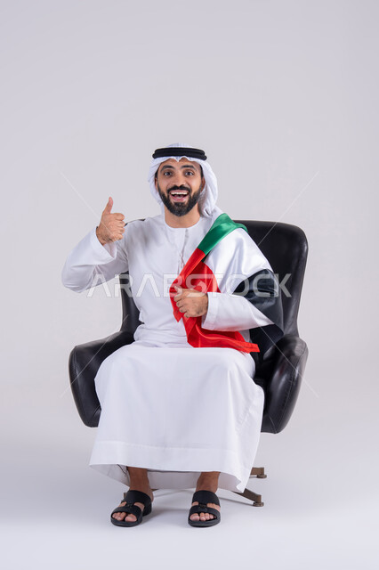 مفهوم الأندية والتشجيع ، ايماءات وجه تدل على النصر , متابعة المباراة و دعم وتشجيع المنتخب العربي , بورتريه لرجل عربي خليجي اماراتي يرتدي الكندوره والغتره ، يشاهد مباراة للدوري العربي في المنزل