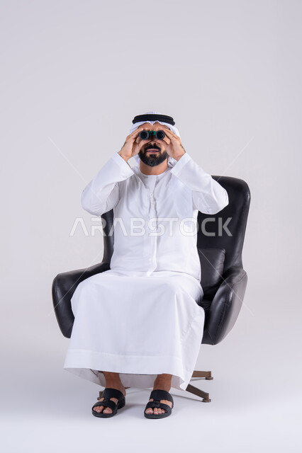 رؤية الاشياء البعيدة وتقريبها، حب الاستكشاف والمغامرة، بورتريه لرجل عربي خليجي اماراتي يرتدي الكندوره والغتره، يحمل بيده منظار ثنائي العينين وينظر بإيماءات السرور والاستمتاع