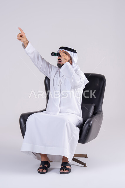حب الاستكشاف والمغامرة، رؤية الاشياء البعيدة وتقريبها،بورتريه لرجل عربي خليجي اماراتي يرتدي الكندوره والغتره، يحمل بيده منظار ثنائي العينين ، ينظر بإيماءات السرور والاستمتاع ويشير الى شئ ما