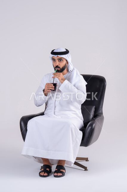 متابعة برامج التلفاز، قضاء وقت ممتع في المنزل، ايماءات التعجب والدهشة، انشطة ترفيهية منزلية، تناول المشروبات البارده ، بورتريه لرجل عربي خليجي اماراتي يرتدي الكندوره والغتره ، يستمتع بمشاهدة الأفلام والمسلسلات