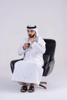 متابعة برامج التلفاز، قضاء وقت ممتع في المنزل، ايماءات التعجب والدهشة، انشطة ترفيهية منزلية، تناول المشروبات البارده ، بورتريه لرجل عربي خليجي اماراتي يرتدي الكندوره والغتره ، يستمتع بمشاهدة الأفلام والمسلسلات