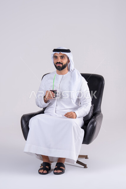 قضاء وقت ممتع في المنزل،متابعة برامج التلفاز، ايماءات التعجب والدهشة، انشطة ترفيهية منزلية، تناول المشروبات البارده ، بورتريه لرجل عربي خليجي اماراتي يرتدي الكندوره والغتره ، يستمتع بمشاهدة الأفلام والمسلسلات