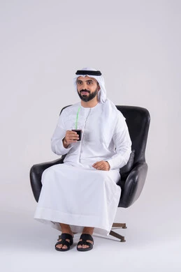 قضاء وقت ممتع في المنزل،متابعة برامج التلفاز، ايماءات التعجب والدهشة، انشطة ترفيهية منزلية، تناول المشروبات البارده ، بورتريه لرجل عربي خليجي اماراتي يرتدي الكندوره والغتره ، يستمتع بمشاهدة الأفلام والمسلسلات