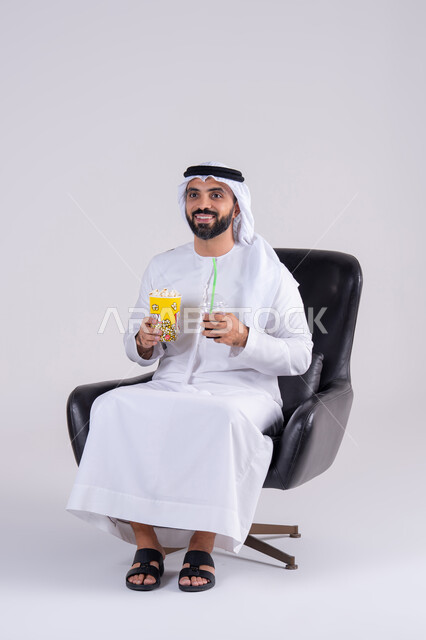 انشطة ترفيهية منزلية، ايماءات التعجب والدهشة، تناول الفوشار والمشروبات الباردة، بورتريه لرجل عربي خليجي اماراتي يرتدي الكندوره والغتره، يستمتع بمشاهدة الأفلام والمسلسلات، متابعة برامج التلفاز، قضاء وقت ممتع في المنزل