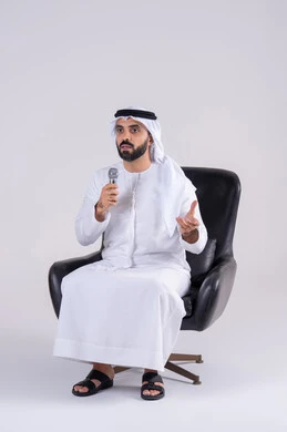 تسجيل مقطع صوتي غنائي،تقديم العروض الصوتية، تعابير الاندماج والتفاعل مع الموسيقي اثناء الغناء، ممارسة موهبة الغناء، بورتريه لرجل عربي خليجي اماراتي يرتدي الكندوره والغتره يمسك بيده المايكروفون