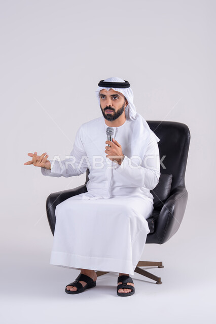 تعابير الاندماج والتفاعل مع الموسيقي اثناء الغناء، ممارسة موهبة الغناء،  تسجيل مقطع صوتي غنائي،بورتريه لرجل عربي خليجي اماراتي يرتدي الكندوره والغتره يمسك بيده المايكروفون ، تقديم العروض الصوتية