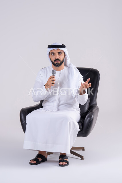 ممارسة موهبة الغناء،  تسجيل مقطع صوتي غنائي،بورتريه لرجل عربي خليجي اماراتي يرتدي الكندوره والغتره يمسك بيده المايكروفون ، تعابير الاندماج والتفاعل مع الموسيقي اثناء الغناء، تقديم العروض الصوتية