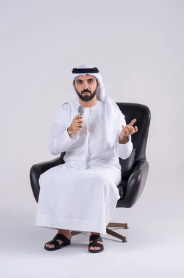 ممارسة موهبة الغناء،  تسجيل مقطع صوتي غنائي،بورتريه لرجل عربي خليجي اماراتي يرتدي الكندوره والغتره يمسك بيده المايكروفون ، تعابير الاندماج والتفاعل مع الموسيقي اثناء الغناء، تقديم العروض الصوتية