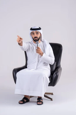 Pointing the index finger, recording a vocal clip, practicing singing talent, portrait of an Emirati Gulf Arab man wearing a kandura and ghutra holding a microphone, expressions of integration and interaction with the music while singing, vocal performances.