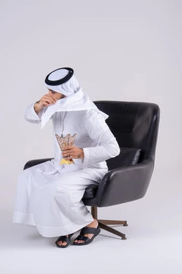 The ancient customs and traditions of the Emirates, looking with gestures of joy and happiness, a portrait of an Arab Gulf Emirati man wearing a kandura and ghutra, burning oud wood during holidays and special occasions, and using incense and perfume (mabkhara).