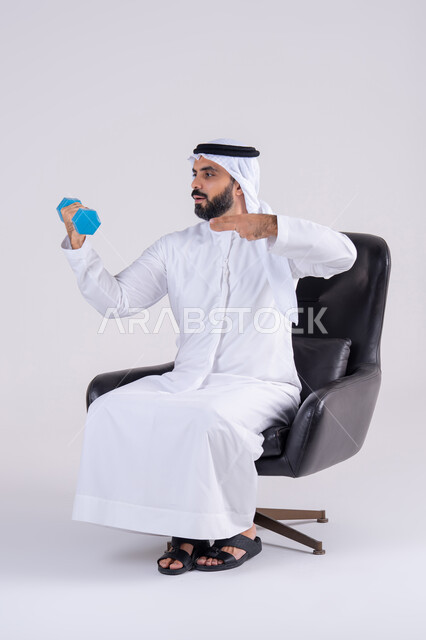 تمارين رفع الأثقال (دمبلز)،ممارسة التمارين الرياضية مع الدمبل،  بورتريه لرجل عربي خليجي اماراتي يرتدي الكندوره والغتره ، يقوم برفع الأوزان الحديدية الثقيلة، المحافظة على الصحة واللياقة الجسدية