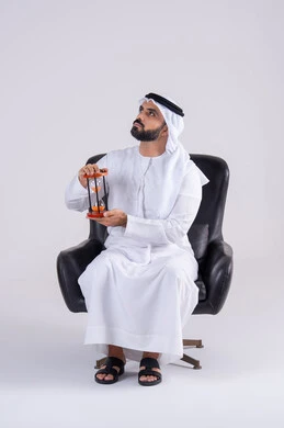 Realizing the value of precious moments, the concept of business management and scheduling, monitoring sand time, portrait of an Emirati Gulf Arab man wearing a kandura and ghutra, holding a glass sandglass (bankam), looking with concentration gestures.