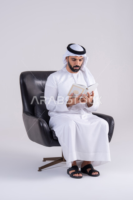 قضاء وقت الفراغ بالتثقيف والتعلم، التزود بالعلم والمعرفة،مفهوم العلم والدين والثقافه، بورتريه لرجل عربي خليجي اماراتي يرتدي الكندوره والغتره يجلس على كرسي، يمارس هواية مطالعة الكتب المفيدة في وقت الفراغ، إيماءات التمعن والتركيز