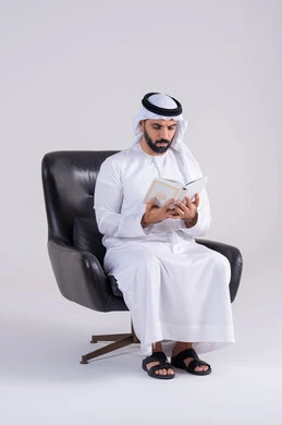 قضاء وقت الفراغ بالتثقيف والتعلم، التزود بالعلم والمعرفة،مفهوم العلم والدين والثقافه، بورتريه لرجل عربي خليجي اماراتي يرتدي الكندوره والغتره يجلس على كرسي، يمارس هواية مطالعة الكتب المفيدة في وقت الفراغ، إيماءات التمعن والتركيز