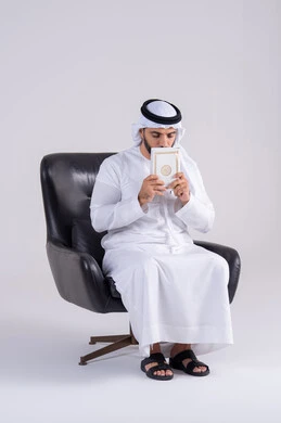 التزود بالعلم والمعرفة،مفهوم العلم والدين والثقافه، قضاء وقت الفراغ بالتثقيف والتعلم،بورتريه لرجل عربي خليجي اماراتي يرتدي الكندوره والغتره يجلس على كرسي ويمسك بيده كتاب ، هواية مطالعة الكتب المفيدة في وقت الفراغ، إيماءات التمعن والتركيز