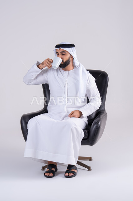 الحيوية والنشاط عند شرب الكافيين، الاستمتاع والاحساس بالدفء ،بورتريه لرجل عربي خليجي اماراتي يرتدي الكندوره والغتره يحمل بيده كوب القهوة بتعابير السرور، احتساء المشروبات الساخنة