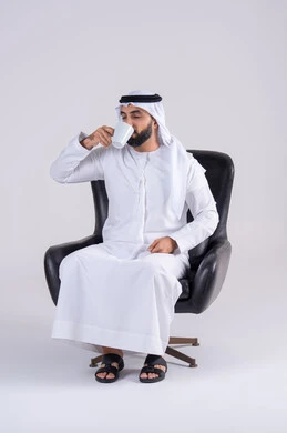 الحيوية والنشاط عند شرب الكافيين، الاستمتاع والاحساس بالدفء ،بورتريه لرجل عربي خليجي اماراتي يرتدي الكندوره والغتره يحمل بيده كوب القهوة بتعابير السرور، احتساء المشروبات الساخنة