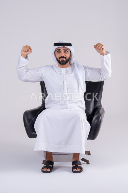 متابعة المباراة و دعم وتشجيع المنتخب العربي , بورتريه لرجل عربي خليجي اماراتي يرتدي الكندوره والغتره يشاهد مباراة للدوري العربي في المنزل, ايماءات وجه تدل على النصر , مفهوم الأندية والتشجيع