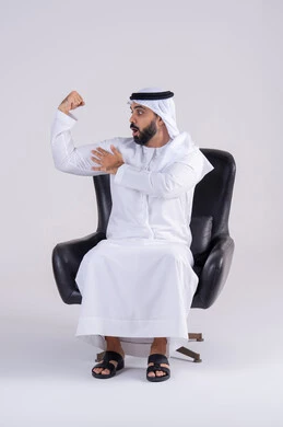 رياضة كمال الأجسام، اللياقة البدنية للاعبين، بناء جسم رياضي، بورتريه لرجل عربي خليجي اماراتي يرتدي الكندوره والغتره يعرض عضلات يده