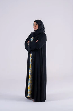 الاهتمام بالاناقة والاهتمام بالمظهر الخارجي، بورتريه من الجانب لامراه عربيه خليجيه اماراتيه ترتدي العباءه والحجاب تقف بايدي متقاطعه وإيماءات الثقة بالنفس ، سيده سعوديه تنظر بتعابير السرور والسعاده