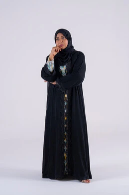 Anxiety and confusion in making the right decision, trying to find a solution to difficult problems, deep thinking and absent-mindedness. Portrait of an Emirati Gulf Arab woman wearing an abaya and hijab, placing her hand under her chin. A Saudi woman standing with an expression of integration.
