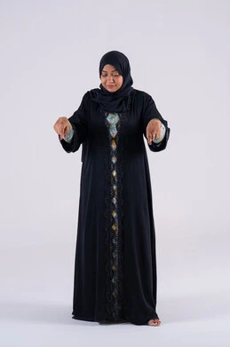 A Saudi woman identifies a specific location, expressions that identify this place here. A portrait of an Emirati Gulf Arab woman wearing an abaya and hijab, pointing her index finger down at something, looking at the camera with gestures of joy and pleasure.