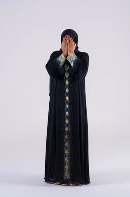 مفهوم الحمد والشكر وطلب العون ,  بورتريه لمرأه عربية خليجية اماراتية ترتدي العباءة والحجاب ترفع يدها بإيماءات الدعاء والتضرع الى الله, التعبد لله  والرغبه في تحقيق الأمنيات, سيده سعوديه تقف بتعابير طلب المغفره