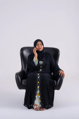 اجراء مكالمه هاتفيه ،تصفح مواقع وتطبيقات الانترنت، الدردشة والتحدث مع الأصدقاء،بورتريه لامراه عربيه خليجيه اماراتيه ترتدي العباءه والحجاب تجلس على كرسي ، تمسك الجوال بيدها، سيده سعوديه تستخدم التقنيات والتكنولوجيا الحديثة بالحياة اليومية