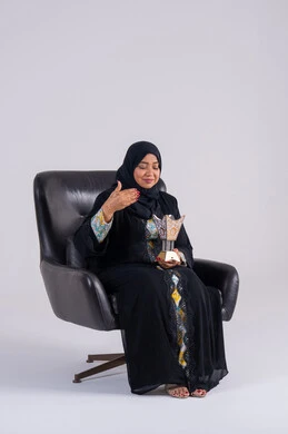 Looking at the gestures of joy and happiness, the ancient customs and traditions of the Emirates, a portrait of an Arab Gulf Emirati woman wearing an abaya and hijab, burning oud wood during holidays and occasions, a Saudi woman sitting on a comfortable chair, applying incense and perfuming herself with incense (incense burner).