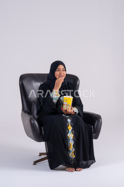 ايماءات التعجب والدهشة،  انشطة ترفيهية منزلية،سيده سعوديه تتناول الفوشار والمشروبات الباردة، بورتريه لامراه عربيه خليجيه اماراتيه ترتدي العباءه والحجاب ، تستمتع بمشاهدة الأفلام والمسلسلات، متابعة برامج التلفاز، قضاء وقت ممتع في المنزل