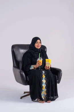 انشطة ترفيهية منزلية، ايماءات التعجب والدهشة، سيده سعوديه تتناول الفوشار والمشروبات الباردة، بورتريه لامراه عربيه خليجيه اماراتيه ترتدي العباءه والحجاب ، تستمتع بمشاهدة الأفلام والمسلسلات، متابعة برامج التلفاز، قضاء وقت ممتع في المنزل