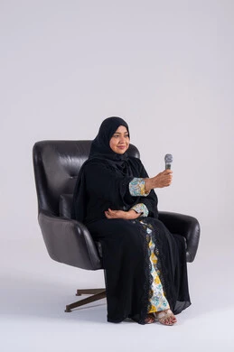 Recording a singing voice clip, practicing singing talent, a portrait of an Arab Gulf Emirati woman wearing an abaya and hijab holding a microphone, a Saudi woman singing with gestures of enthusiasm and pleasure, expressions of integration and interaction with the music, presenting vocal performances.