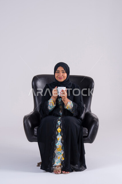 الحيوية والنشاط عند شرب الكافيين،  الاستمتاع والاحساس بالدفء ،بورتريه  لامراه عربيه خليجيه اماراتيه ترتدي العباءه والحجاب تحمل بيدها كوب القهوة بتعابير السرور، سيده سعوديه تقوم باحتساء المشروبات الساخنة
