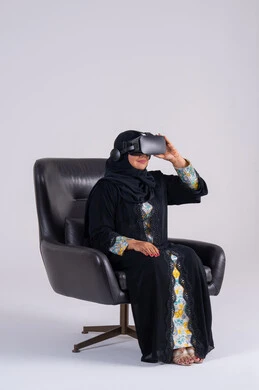 بورتريه لامراه عربيه خليجيه اماراتيه ترتدي العباءه والحجاب تضع نظارات ثلاثية الأبعاد، المتعة والتسلية بالمشاهدة عبر نظارة الواقع الافتراضي, سيده سعوديه  تنظر بتعابير الاندماج