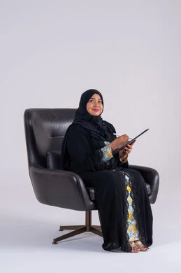 تدوين وتسجيل الملاحظات والمعلومات على الورق ، سيده سعوديه تستخدم الاوراق البيضاء الفارغة في العمل، إدارة الأعمال وتنظيمها،  بورتريه لامراه عربيه خليجيه اماراتيه  ترتدي العباءه والحجاب تجلس على كرسي ، وتقوم بكتابة المهام والأهداف اليومية