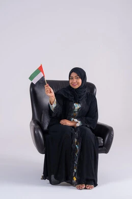 هوية اليوم الوطني الاماراتي 2 ديسمبر، رفع العلم بايماءات الاعتزاز والثقة، احياء ذكرى استقلال الإمارات 1971، الحب والانتماء للوطن، تعابير السرور والفخر والسعاده،  بورتريه لسيده عربية خليجية اماراتيه محجبة تمسك بيدها علم الإمارات