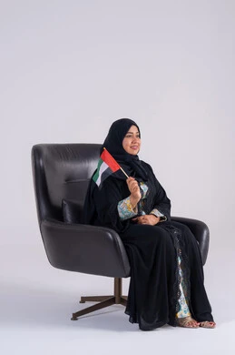 احياء ذكرى استقلال الإمارات 1971، الحب والانتماء للوطن، تعابير السرور والفخر والسعاده، النظر بايماءات الاعتزاز والثقة، بورتريه لسيده عربية خليجية اماراتيه محجبة تمسك بيدها علم الإمارات ، هوية اليوم الوطني الاماراتي 2 ديسمبر