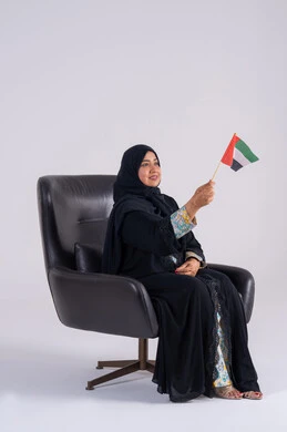 الحب والانتماء للوطن، تعابير السرور والفخر والسعاده، النظر بايماءات الاعتزاز والثقة، بورتريه لسيده عربية خليجية اماراتيه محجبة تمسك بيدها علم الإمارات ، هوية اليوم الوطني الاماراتي 2 ديسمبر، احياء ذكرى استقلال الإمارات 1971