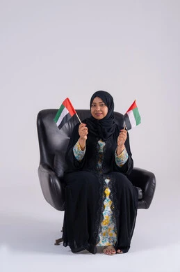 بورتريه لسيده عربية خليجية اماراتيه محجبة تمسك بيدها علم الإمارات ، هوية اليوم الوطني الاماراتي 2 ديسمبر، ايماءات الاعتزاز والثقة، احياء ذكرى استقلال الإمارات 1971، الحب والانتماء للوطن