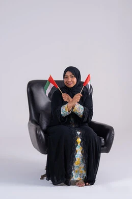 هوية اليوم الوطني الاماراتي 2 ديسمبر، ايماءات الاعتزاز والثقة، احياء ذكرى استقلال الإمارات 1971، الحب والانتماء للوطن،بورتريه لسيده عربية خليجية اماراتيه محجبة تمسك بيدها علم الإمارات