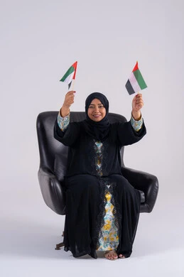 ايماءات الاعتزاز والثقة، احياء ذكرى استقلال الإمارات 1971، الحب والانتماء للوطن،بورتريه لسيده عربية خليجية اماراتيه محجبة تمسك بيدها علم الإمارات ، هوية اليوم الوطني الاماراتي 2 ديسمبر