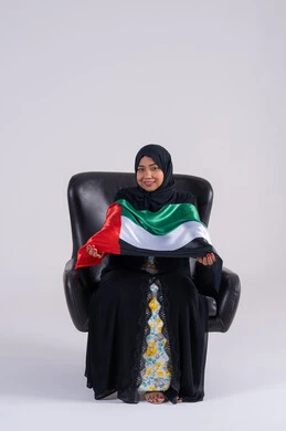 الحب والانتماء للوطن، احياء ذكرى استقلال الإمارات 1971، بورتريه لسيده عربية خليجية اماراتيه محجبة تحمل علم الإمارات ، النظر الى الكاميرا بايماءات الاعتزاز والثقة، هوية اليوم الوطني الاماراتي 2 ديسمبر