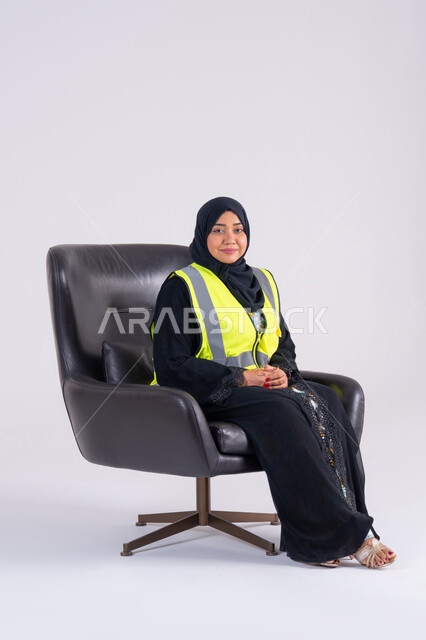 العمل في القطاع الهندسي، مفهوم الهندسة والانشاءات المعمارية، سيده اماراتيه تنظر بايماءات الفخر، تعابير السرور والسعادة والثقة بالنفس،بورتريه لمهندسة عربية خليجية سعودية محجبة ترتدي سترة الحماية